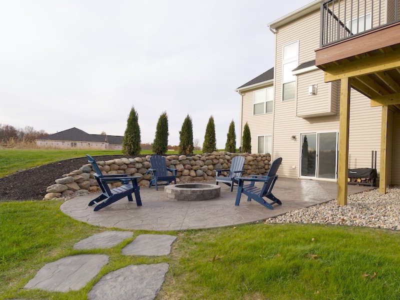 Paver patio, boulder retaining wall and brick fire pit in Brighton